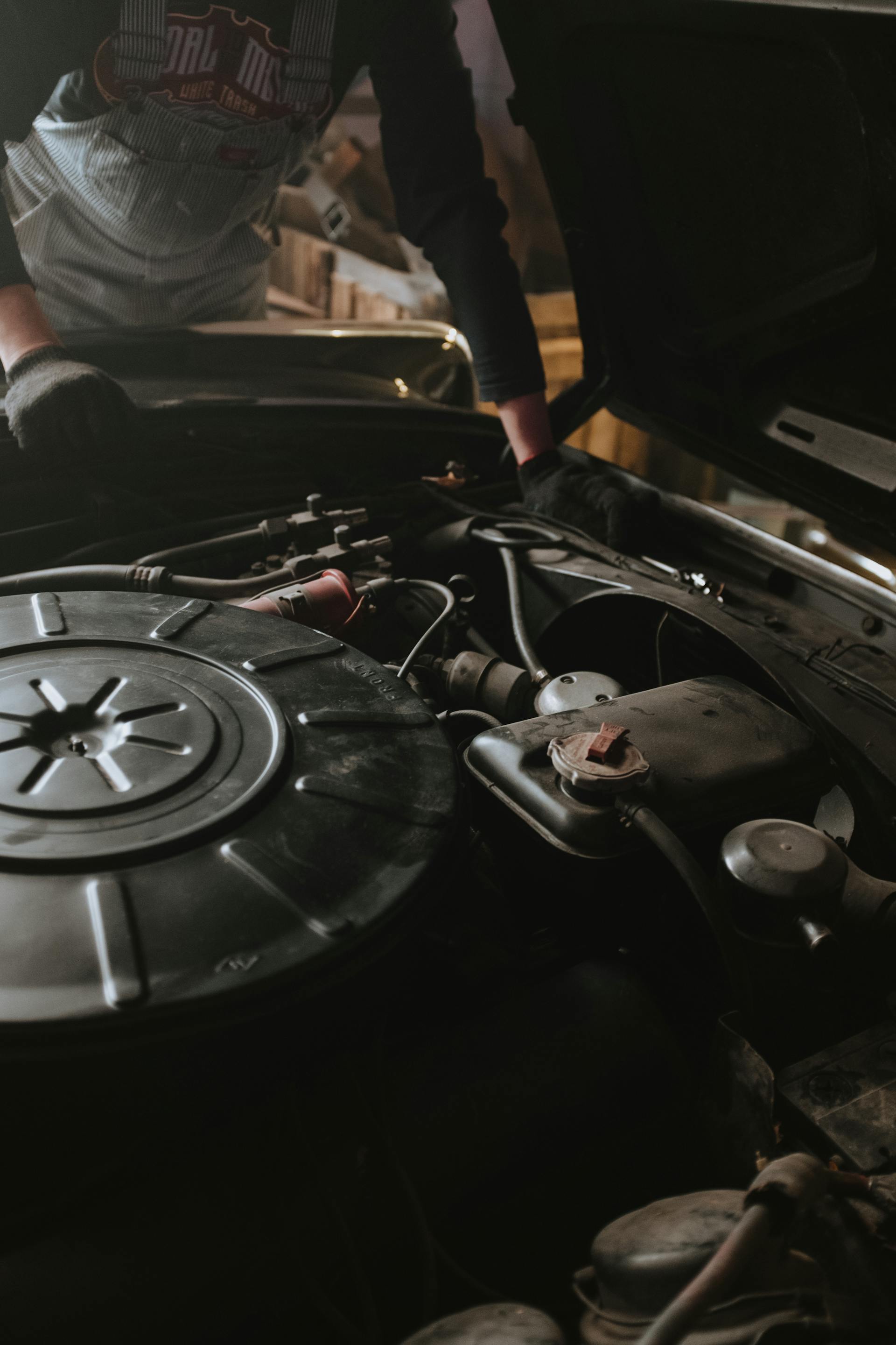 Mechanic working on vehicle electrical system under the hood